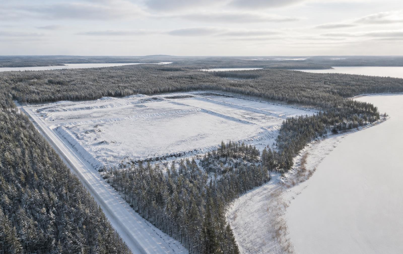 Aerial view of a cleared industrial development plot in a snowy Finnish forest landscape